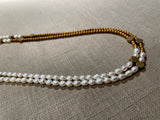 side top view of gemstone bead necklace comprising white pearl, gold and silver hematite and bronze dot accents. 