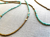 closeup view of gemstone bead necklace comprising aqua amazonite, gold hematite and bronze dot accents. 