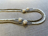 side view of gemstone bead necklace comprising hand-sewn pearl clusters, white mother of pearl, light gold hematite and silver hematite