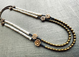 top view of gemstone bead necklace comprising antique hand-carved bone flowers, white pearl and gold hematite