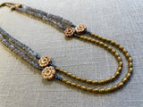 top view of gemstone bead necklace comprising antique hand-carved bone flowers, grey moonstone and gold hematite