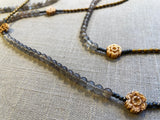 closeup top view of gemstone bead necklace comprising antique hand-carved bone flowers, grey moonstone and gold hematite