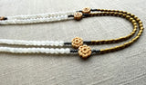 side view of gemstone bead necklace comprising antique hand-carved bone flowers, white rainbow moonstone and gold hematite