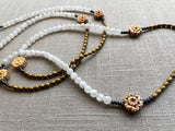closup view of gemstone bead necklace comprising antique hand-carved bone flowers, white rainbow moonstone and gold hematite