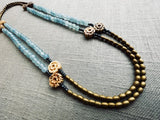  top view of gemstone bead necklace comprising antique hand-carved bone flowers, blue aquamarine and gold hematite