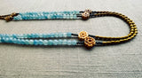  side view of gemstone bead necklace comprising antique hand-carved bone flowers, blue aquamarine and gold hematite
