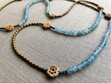  closeup view of gemstone bead necklace comprising antique hand-carved bone flowers, blue aquamarine and gold hematite