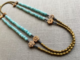  top view of gemstone bead necklace comprising antique hand-carved bone flowers, blue larimar and gold hematite