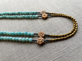  side view of gemstone bead necklace comprising antique hand-carved bone flowers, blue larimar and gold hematite