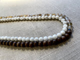 side view of gemstone bead necklace comprising light yellow rutilated quartz, white moonstone and brown exotic wood. 