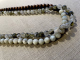 side  view of gemstone bead necklace comprising green tourmaline, white siberian moonstone and brown exotic wood. 