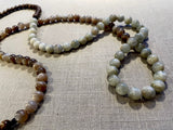 closeup view of gemstone bead necklace comprising peach moonstone, white siberian moonstone and brown exotic wood. 