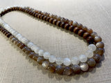 top view of gemstone bead necklace comprising peach moonstone, white moonstone and brown exotic wood. 