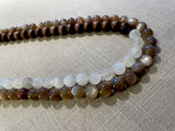 side view of gemstone bead necklace comprising peach moonstone, white moonstone and brown exotic wood. 