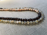 side view of gemstone bead necklace comprising pink opal, light yellow rutilated quartz and brown exotic wood. 
