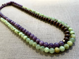 top view of gemstone bead necklace comprising purple lepidolite, green calcite and brown exotic wood. 