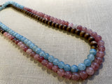 top view of gemstone bead necklace comprising pink strawberry quartz, blue calcite and brown exotic wood. 