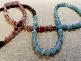 closeup view of gemstone bead necklace comprising pink strawberry quartz, blue calcite and brown exotic wood. 