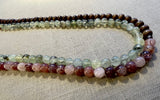 side view of gemstone bead necklace comprising pink strawberry quartz, green prehnite and brown exotic wood. 