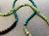 closeup view of gemstone bead necklace comprising green calcite, turquoise and brown exotic wood. 