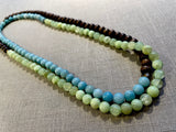 top view of gemstone bead necklace comprising blue larimar, green calcite and brown exotic wood. 