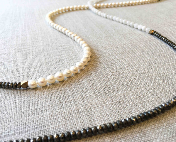 closeup of gemstone bead necklace comprising white pearl, dark silver pyrite and exotic wood