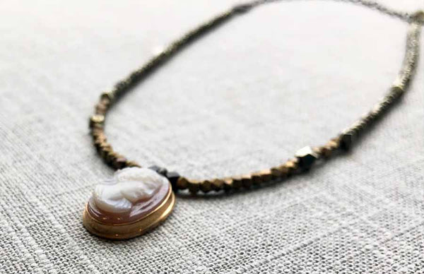 closeup of antique cameo pendant hung on metallic bead choker
