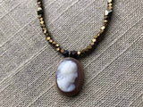 closeup of antique cameo pendant hung on metallic bead choker