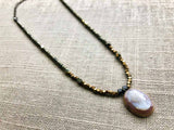 top view of antique cameo pendant hung on metallic bead choker