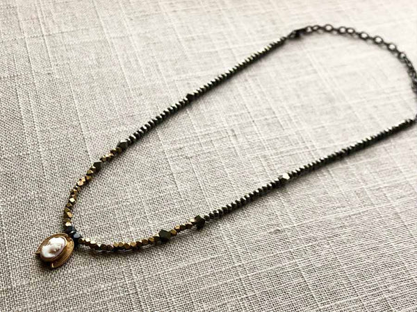 top view of antique cameo pendant hung on metallic bead choker