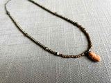 top view of antique coral cameo pendant hung on a metallic bead choker