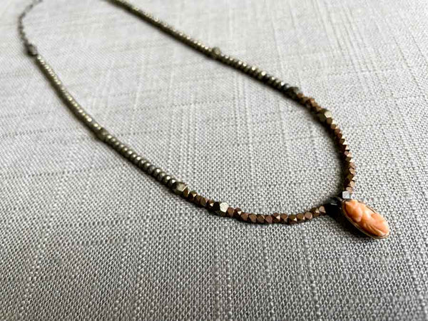 top view of antique coral cameo pendant hung on a metallic bead choker