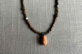 closeup of antique coral cameo pendant hung on a metallic bead choker
